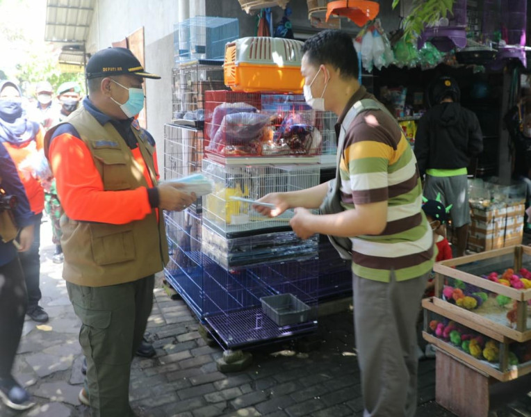 Deputi Bidang Rehabilitasi dan Rekonstruksi BNPB Jarwansyah memberikan masker kepada pembeli di Pasar Satwa PASTY, Yogyakarta, Minggu (27/2).