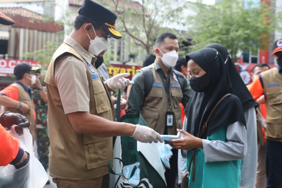 Kepala BNPB Letjen TNI Suharyanto (menggunakan rompi cokelat dan topi hitam) memberikan masker dan berdiskusi dengan wisatawan di jalan Malioboro, Yogyakarta (27/2).