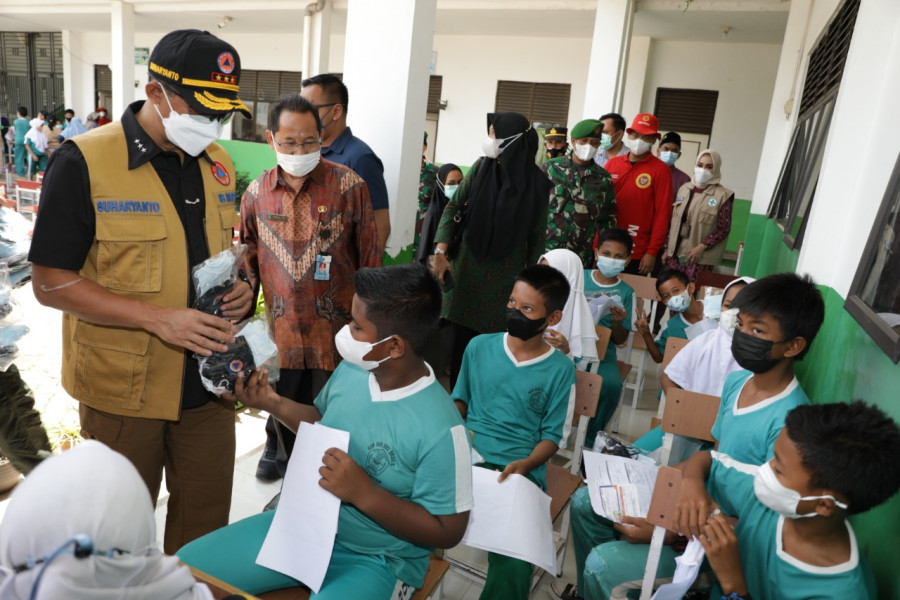 Kepala BNPB sekaligus Ketua Satgas Penanganan Covid-19 Letjen TNI Suharyanto (kiri) memberikan masker gratis kepada seorang siswa yang telah menerima vaksin Covid-19 di SD 006 Sei Beduk, Kota Batam, Kepulauan Riau, Kamis (24/3).
