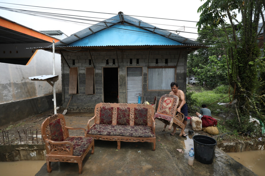 Warga membersihkan perabot rumah tangga yang terdampak banjir di Jalan Raya Bailang, Lingkungan 1, Kelurahan Bailang, Kecamatan Bunaken, Kota Manado, Sulawesi Utara, Sabtu (28/1).