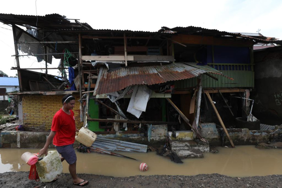 Warga beraktivitas di depan rumahnya yang porak poranda terdampak banjir di Jalan Raya Bailang, Lingkungan 1, Kelurahan Bailang, Kecamatan Bunaken, Kota Manado, Sulawesi Utara, Sabtu (28/1).