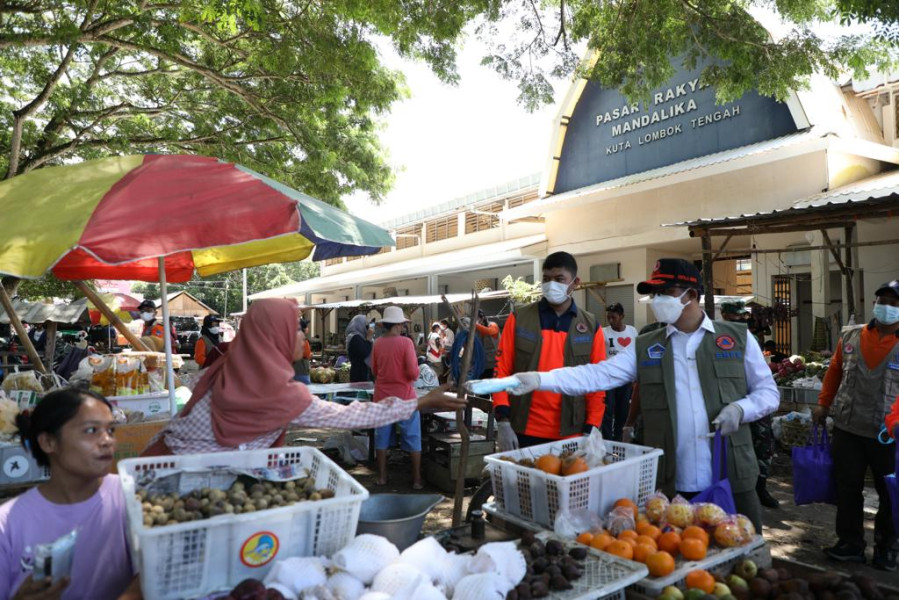 Kepala BNPB Letjen TNI Suharyanto (kiri) membagikan masker kepada salah satu pedagang di Pasar Rakyat Mandalika, Lombok Tengah, Nusa Tenggara Barat, Selasa (15/3).