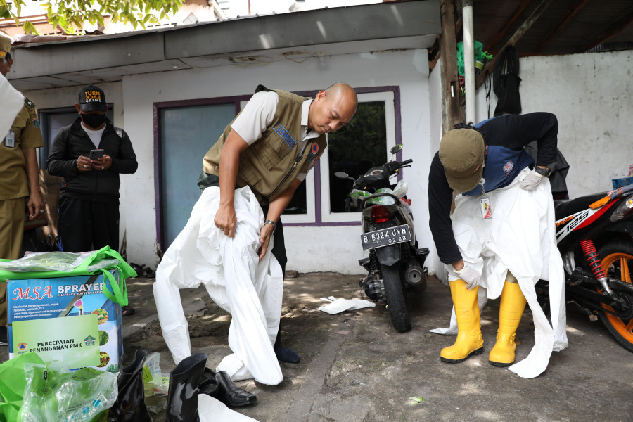 Petugas Monev Satgas PMK menggunakan APD sebagai langkah penerapan biosecurity sebelum melakukan pengecekan hewan ternak di Kandang Ternak Sapi Perah, Jakarta Pusat, Senin (10/10).
