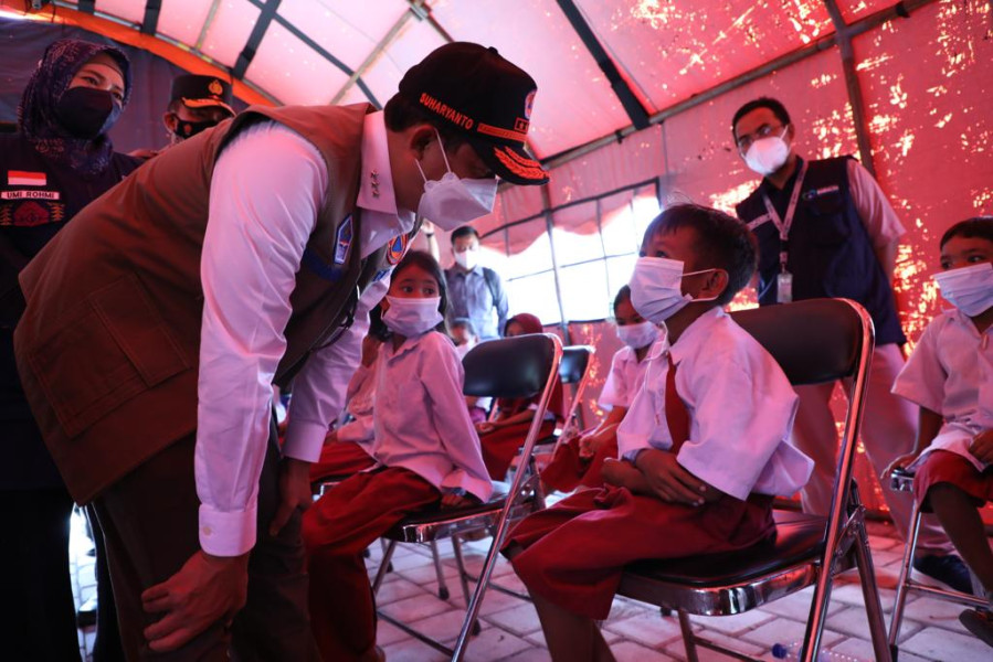 Kepala BNPB Letjen TNI Suharyanto (kiri) berdialog dengan salah satu siswa SD yang menjadi peserta vaksinasi dosis ke-3 di Rumah Sakit Umum Daerah (RSUD) Mandalika, Selasa (15/3).