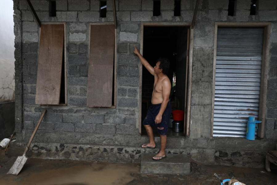 Warga menunjukkan batas ketinggian muka air banjir yang masih tersisa di dinding rumahnya di Jalan Raya Bailang, Lingkungan 1, Kelurahan Bailang, Kecamatan Bunaken, Kota Manado, Sulawesi Utara, Sabtu (28/1).