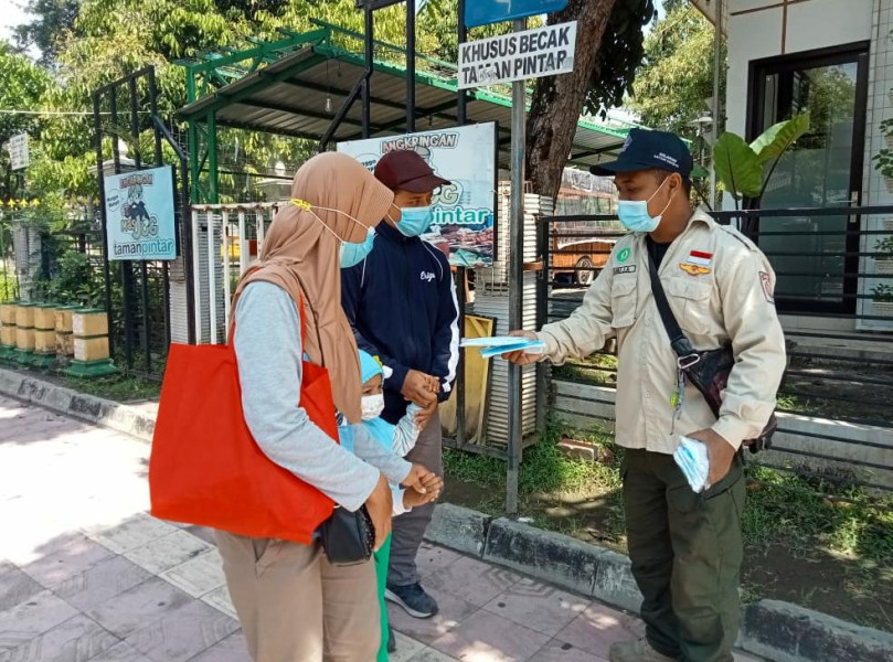 Tim Relawan membagikan masker kepada wisatawan di tempat wisata Taman Pintar, Yogyakarta, Minggu (27/2).