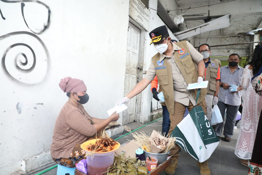 Kepala BNPB Letjen TNI Surhayanto memberikan masker kepada pedagang sate di kawasan Malioboro, Yogyakarta, Minggu (27/2).