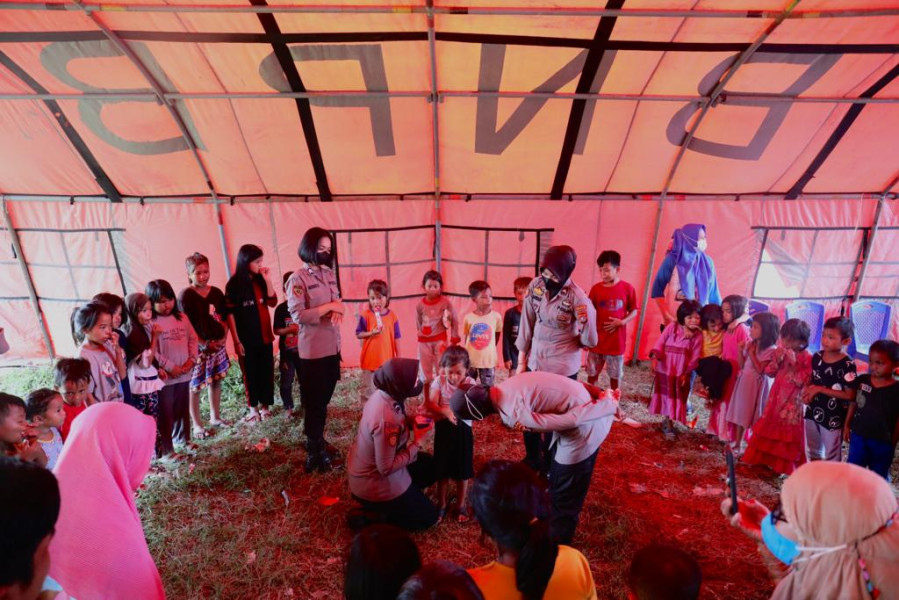 Anggota Polwan dari Polda Sulawesi Barat menghibur anak-anak pengungsian di Stadion Manakarra, Mamuju, Sulawesi Barat, Kamis (9/6).
